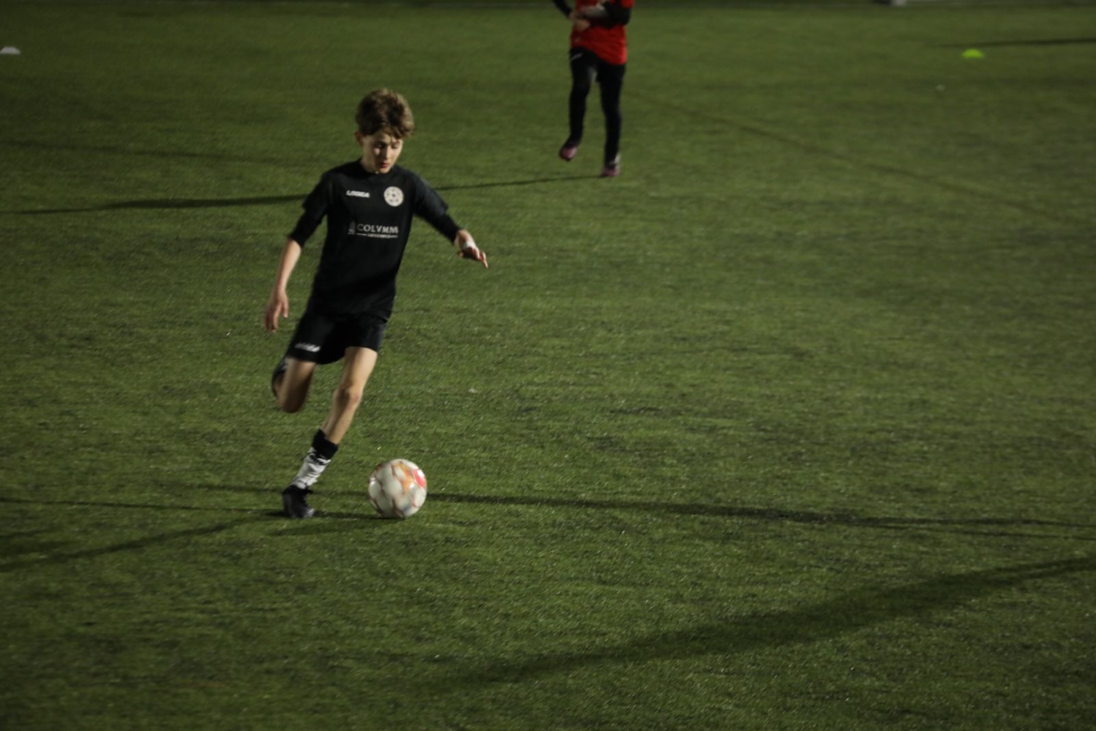 jucător de fotbal îmbrăcat în echipament negru alergând pe teren 